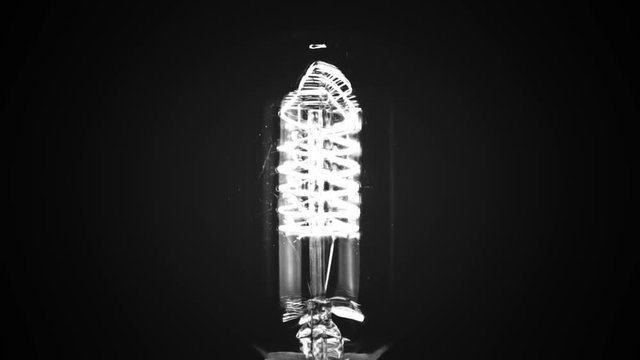 black and white vintage old movie with flicker effect of turn on and turn off in slow motion, retro vintage light bulb with old technology with filament built-in with warm bulb light