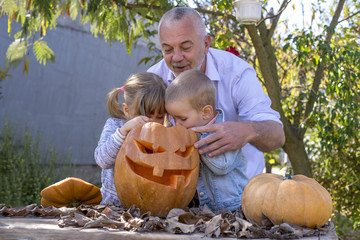 Grandfather carving pumpkins with grandchildren for Halloween