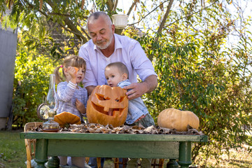Grandfather enjoying with grandchildren while carving pumpkins together