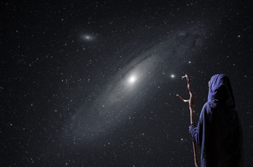 Fototapeta na wymiar eine mystische Person beobachtet nachts den Sternenhimmel mit der Andromedagalaxie