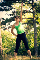 Young beautiful girl doing physical exercises in a park. Summer season