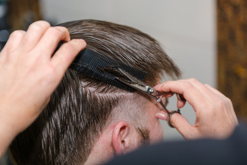 Fototapeta premium Scissor the hair of a man in a barbershop