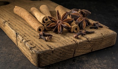 Aniseed star, cinnamon sticks and cloves ingredients for mulled wine on a rustic wooden chopping board.