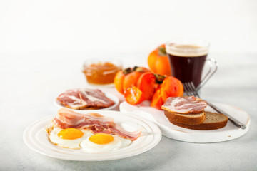 Fried eggs, bacon, a toast, a persimmon