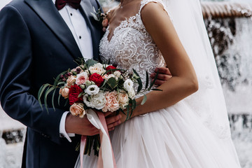 Beautiful couple with a amazing wedding bouquet of red, white, beige roses