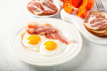 Fried eggs, bacon, a toast, a persimmon