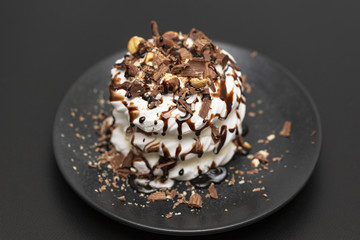 Meringue dessert with chocolate sauce, chocolate, nuts and cream.