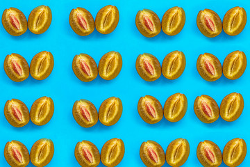 Food pattern of halves of ripe blue plum with bone on bright turquoise paper, minimalism style, top view
