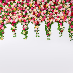 spring and summer background - close up of colorful artificial flowers over white wall with copy space