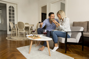 Fototapeta premium Couple relaxing at home and eating tasteful pizza