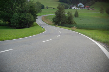 Fototapeta na wymiar A winding asphalt road. Cross lines on road, Close up view of a road in curves