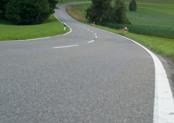 A winding asphalt road. Cross lines on road, Close up view of a road in curves