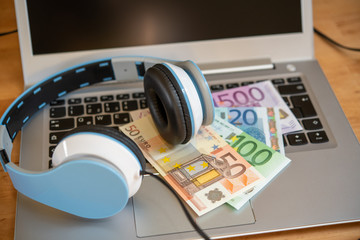computer with headphones and euro bank notes