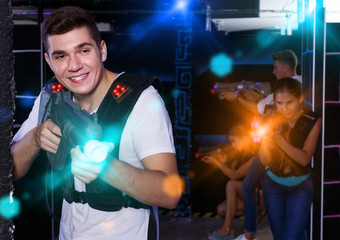 Excited guy holding laser pistol, playing laser tag with friends