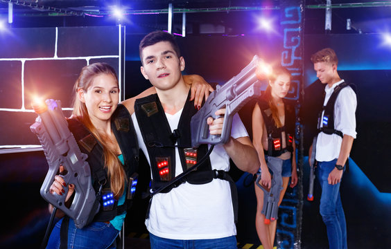 Young guys and girls in vests holding plasticlaser pistols and p