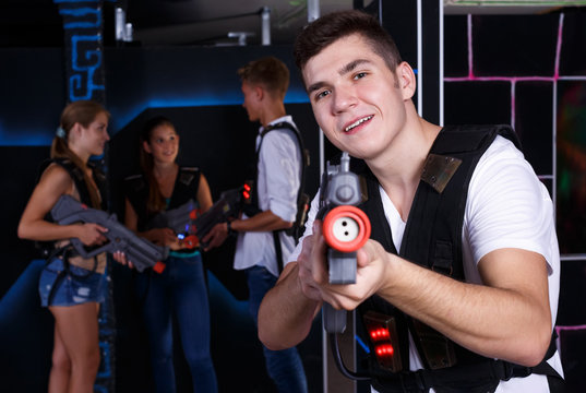 Excited  guy with laser pistol while playing lasertag with his friends