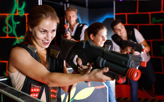 Portrait of exciting girl with laser pistol playing laser tag in dark room
