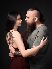 Attractive young couple with tattoos on dark background