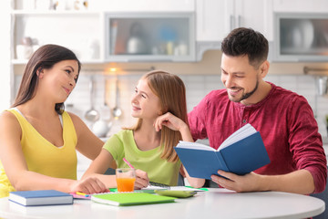 Obraz premium Little girl doing homework with parents