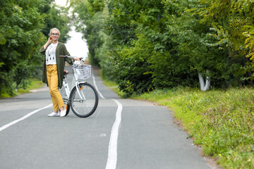 Beautiful woman in casual outfit with bicycle outdoors. Space for text