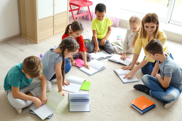 Female teacher helping children with homework in classroom at school