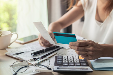 Young woman checking bills, taxes, bank account balance and calculating credit card expenses at home