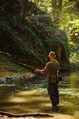 A fisherman fishing with fly fishing in the flowing stream