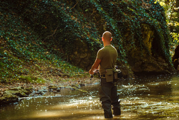 A fisherman fishing with fly fishing in the flowing stream