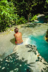 Fototapeta premium Tourist sitting on the rock on the water in erawan waterfall national park kanchanaburi thailand