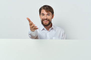 smiling man stretches his hand next to a white loaf of paper