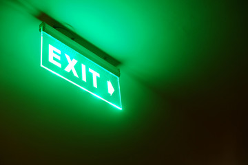 Perspective view of green emergency fire exit sign hanging on the ceiling
