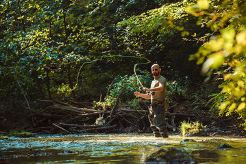 Fototapeta na wymiar A fisherman fishing with fly fishing in the flowing stream