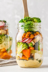 Healthy Homemade Mason Jar Salad with baked vegetables, hummus, tofu and chickpeas.
