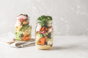 Healthy Homemade Mason Jar Salad with baked vegetables, hummus, tofu and chickpeas, copy space.