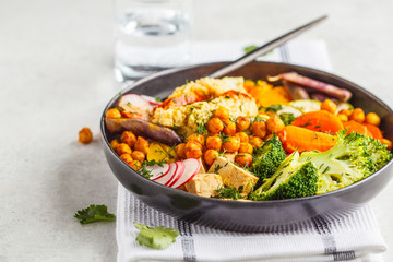 Vegan Buddha bowl with baked vegetables, chickpeas, hummus and tofu.