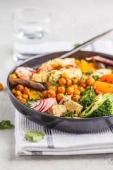 Vegan Buddha bowl with baked vegetables, chickpeas, hummus and tofu.