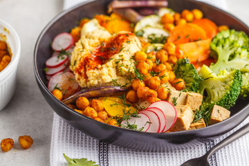 Vegan Buddha bowl with baked vegetables, chickpeas, hummus and tofu.