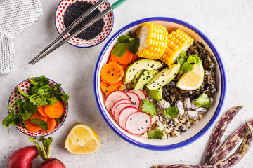 Flat lay vegan poke bowl with brown rice, sea kale and vegetables.