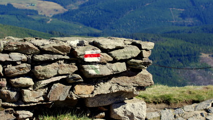 Oznaczenie czerwonego szlaku w polskich górach na kamiennym murku - w wakacje spacerem przez Karkonosze