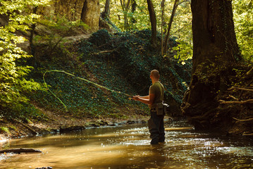 A fisherman fishing with fly fishing in the flowing stream
