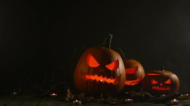 Halloween pumpkins head jack o lantern and candles on dark wooden background