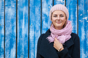 Portrait female student on bright background. Beautiful modern urban young woman wearing pink knitting hat  smile, look at the camera and engoy autumn sunny day.