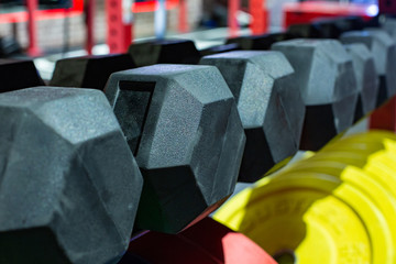 Black rubber dumbbells. Hexagonal heavy duty weight set used for serious hardcore gym workouts,...