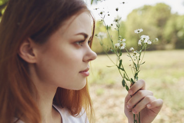 woman holding in the face of wild flowers in nature