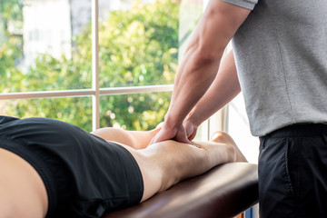 Obraz premium Male therapist giving leg massage to athlete patient in clinic