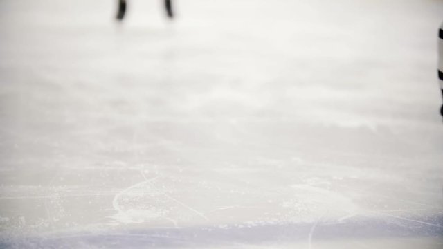 Hockey player riding on ice skating during training. View of legs
