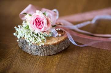 background for the autumn wedding invitation, two wedding rings on a piece of wood decorated with rose flower and ribbons, place for text