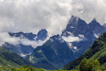 Peak of the mountain with glaciers against the background of clouds and sky. Caucasian ridge, Russia.