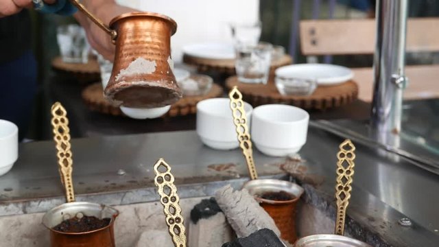 Turkish coffee being brewed by unidentified man on hot sand and  charcoal.