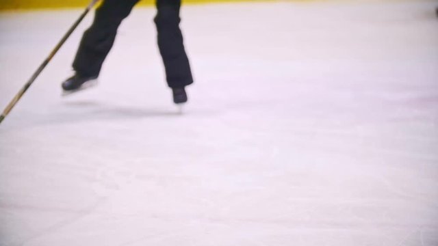 Hockey players drive through a hockey field with a black puck. View of legs
